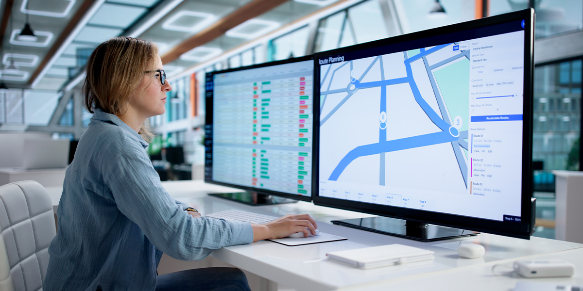 Fleet operations manager monitoring route planning and vehicle data across dual screens, representing AirLink OS 6.1 fleet intelligence and remote diagnostics capabilities.