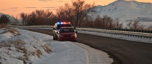 A police cruiser with active emergency lights pursues a vehicle along a snow-covered rural road at dusk, illustrating mission-critical first-responder connectivity scenarios.
