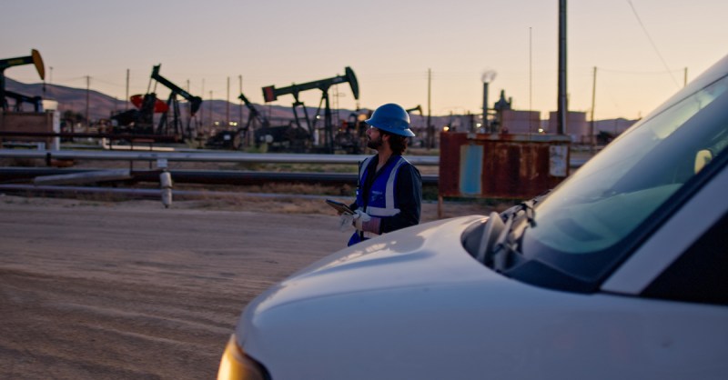Field technician inspecting remote oilfield infrastructure at sunset in Kern County