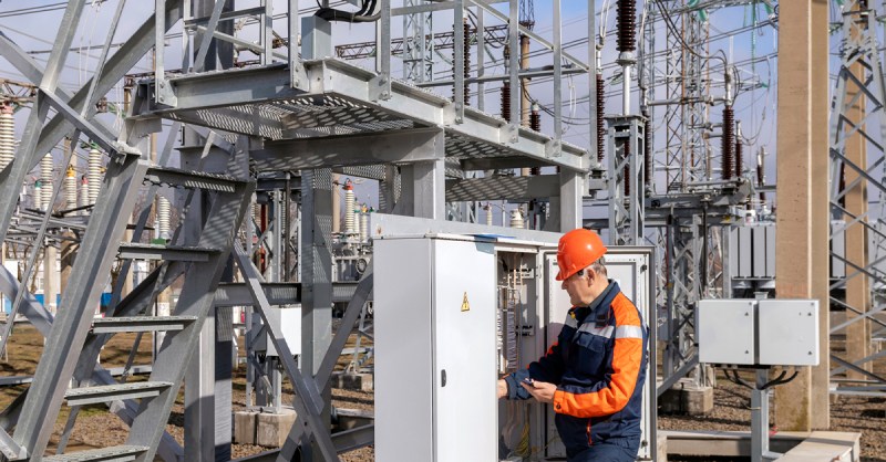 Utility technician inspecting substation control cabinet, representing 5G RedCap deployment for grid automation and industrial IoT